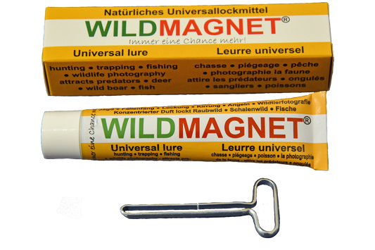 Eine Tube „WILDMAGNET®“ – ein natürliches Universallockmittel – zusammen mit der zugehörigen Verpackung und einem Metallschlüssel zum Ausdrücken der Tube. Die Beschriftung ist mehrsprachig (Deutsch, Englisch, Französisch) und beschreibt die Anwendung für Jagd.