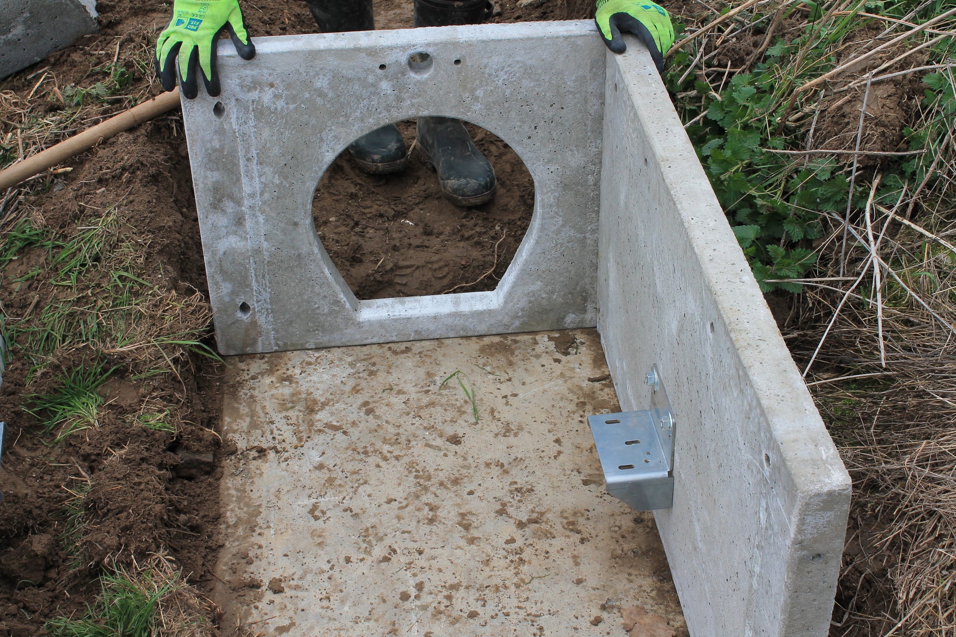 Einbau eines Betonmoduls mit Techniköffnung und seitlicher Halterung für eine modulare Rohrfalle im Erdreich.