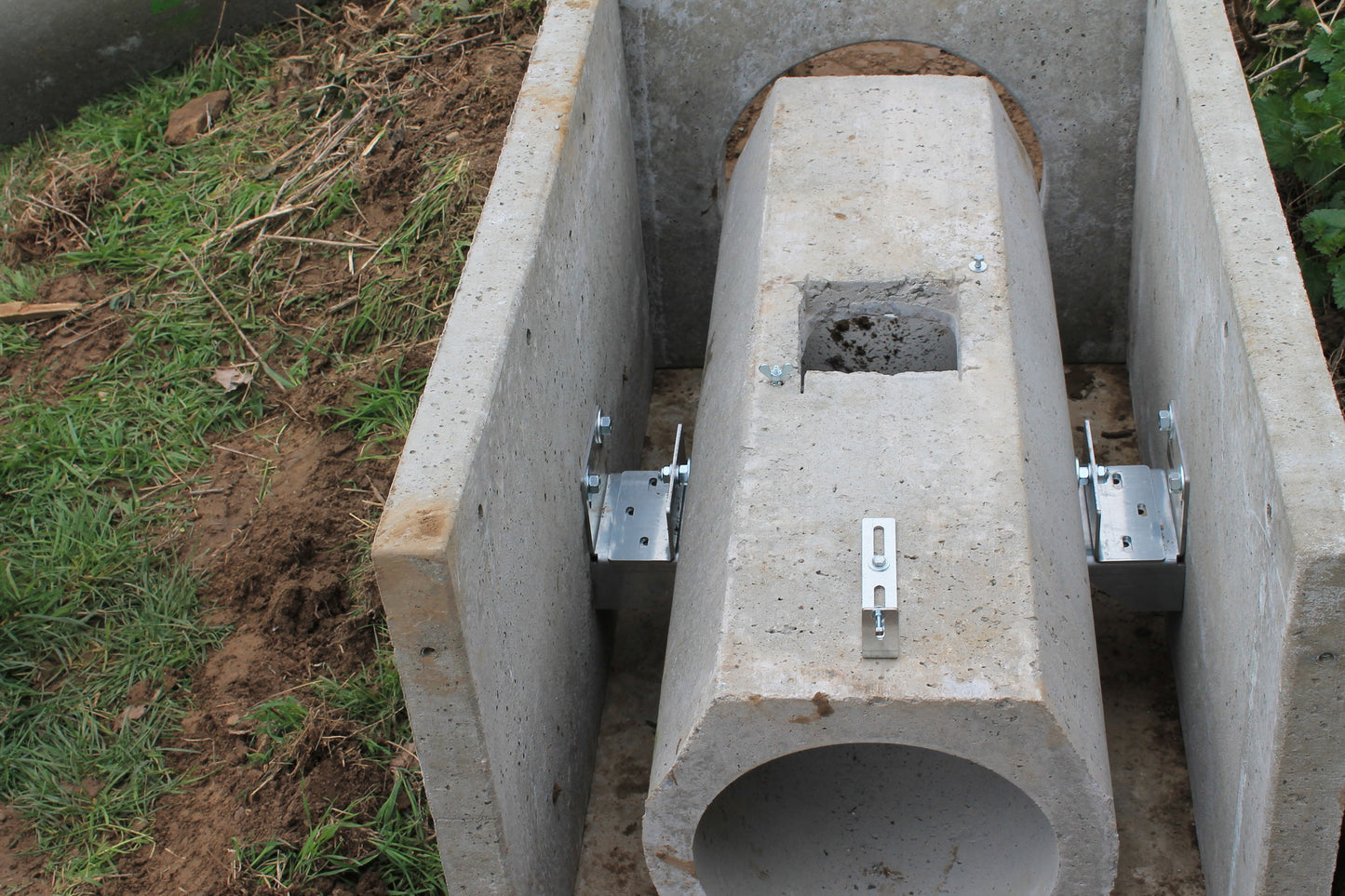 Montierte Betonrohrfalle mit Techniköffnung und seitlichen Metallhalterungen zur Fixierung im Betonmodul.

