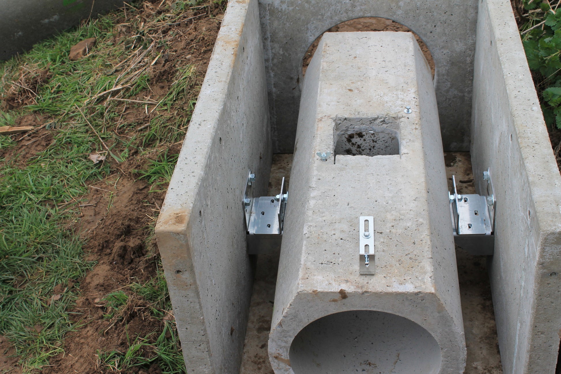 Montierte Betonrohrfalle mit Techniköffnung und seitlichen Metallhalterungen zur Fixierung im Betonmodul.

