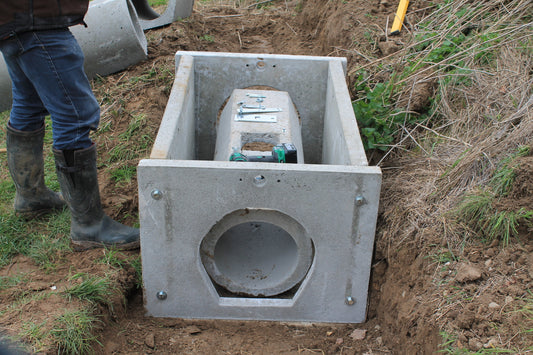 Montiertes Betonfangsystem mit eingebautem Fangmodul und Technikkomponente im Erdreich, vorbereitet zur Rohrverbindung.